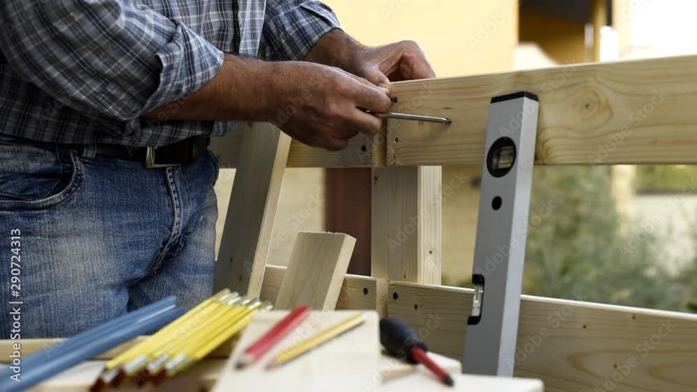 Adult carpenter craftsman with screwdriver screw the screw to fix the boards of a wooden fence. Housework do it yourself. Footage. Adult carpenter craftsman with screwdriver screw the screw to fix the boards of a wooden fence. Housework do it yourself. Footage.