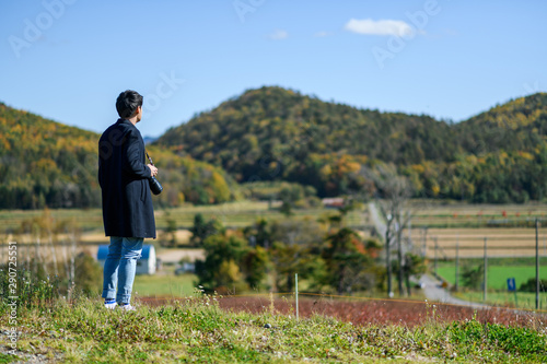 A man stading on the hill with camera looking at the landscape of countryside.