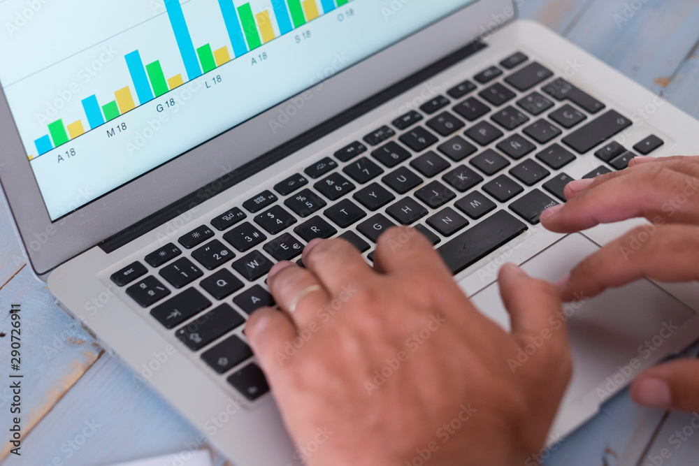 close up of computer or laptop and paper with statistics on a blue table of wood with the hands of one man in the picture - blue table of wood - close up of computer or laptop and paper with statistics on a blue table of wood with the hands of one man in the picture - blue table of wood -