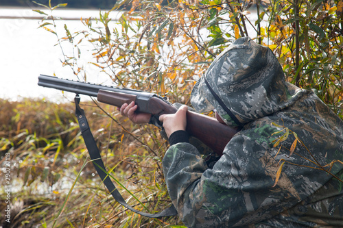 Hunter with a gun. Duck hunting in autumn on the lake.