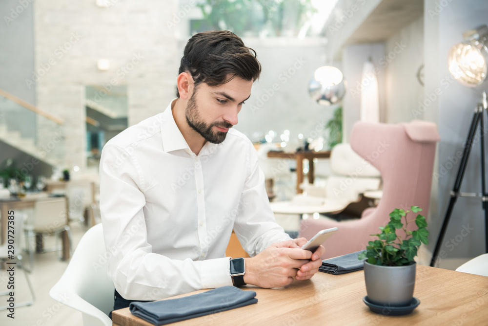 Young Man Sitting in the Restaurant Using Phone Concept