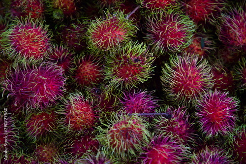 heap of red rambutan in market .