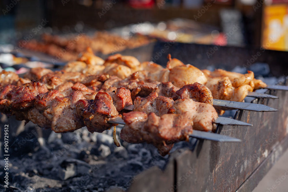 Meat on a skewer is fried on hot charcoal on an iron barbecue. Meat on a skewer is fried on hot charcoal on an iron barbecue.
