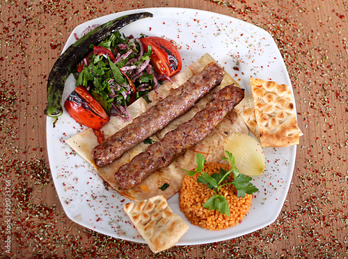 Roasted turkey kebabs  on a wooden table filled with Turkish spices photo