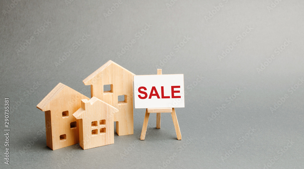 Three wooden houses and a stand with the inscription SALE. selling a home. Announcement of the sale and attracting potential buyers. Advertising campaign. purchase of real estate. Three wooden houses and a stand with the inscription SALE. selling a home. Announcement of the sale and attracting potential buyers. Advertising campaign. purchase of real estate.
