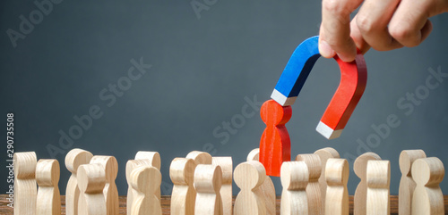 businessman pulls out a red figure of a man from the crowd with the help of a magnet. leader manages the business and forms a team. toxic, incompetent worker. Increase team efficiency, productivity. photo