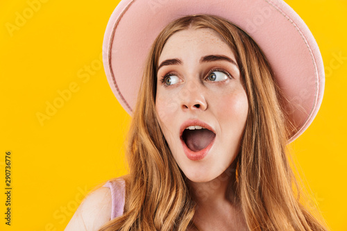 Surprised girl isolated over yellow wall background wearing hat with mouth opened.