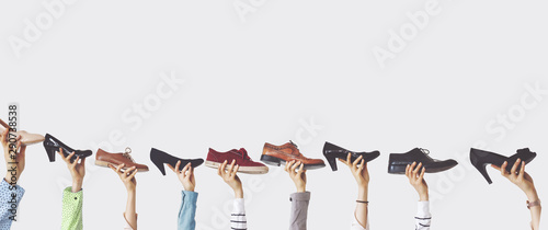Hands holding different shoes on isolated background