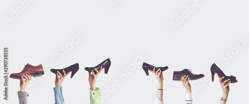 Hands holding different shoes on isolated background