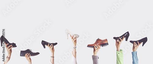 Hands holding different shoes on isolated background