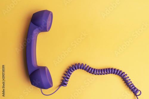 purple telephone receiver on yellow background
