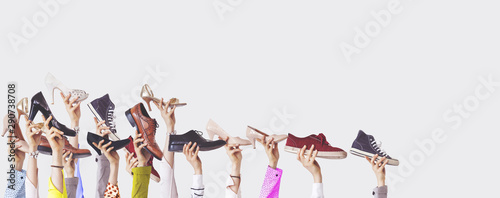 Hands holding different shoes on isolated background