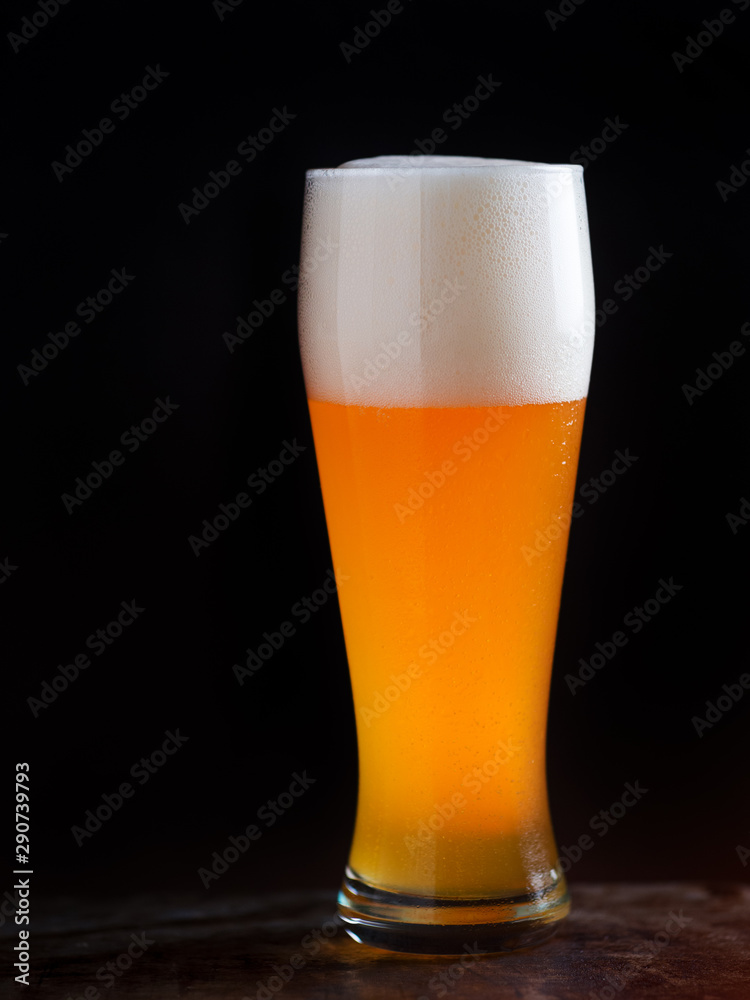 A glass of light beer on a dark background closeup A glass of light beer on a dark background closeup