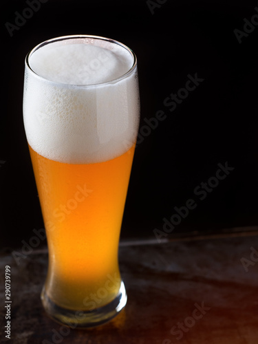 A glass of light beer on a dark background closeup