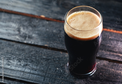 Cuadro en lienzo A glass of dark craft beer porter on a wooden table in a pub with copyspace