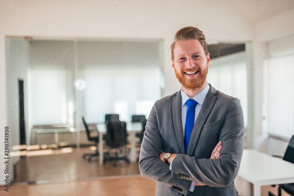 Portrait of a happy manager in formal wear standing with is arms crossed and looking at camera in the office. Portrait of a happy manager in formal wear standing with is arms crossed and looking at camera in the office.