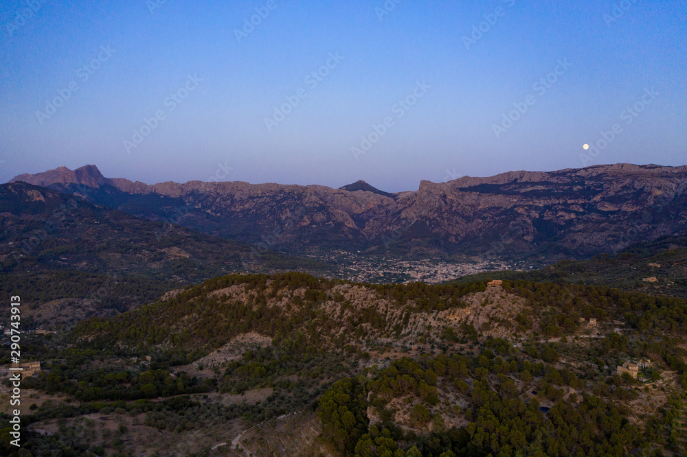 The Tramuntana Mountians at twilight with the moon hovering above them. Dramatic landscape background. The Tramuntana Mountians at twilight with the moon hovering above them. Dramatic landscape background.
