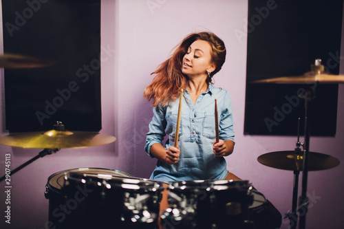 Fototapeta Photograph of a female drummer playing a drum set on stage.