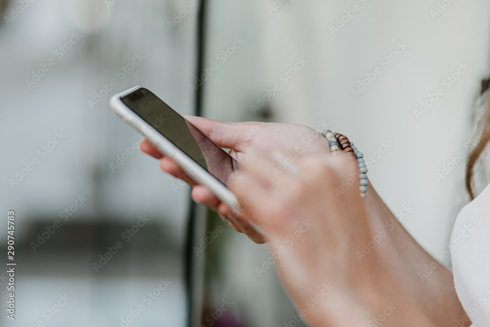 Close up Female hands with bracelets holding smartphone. Woman hand holding mobile phone.