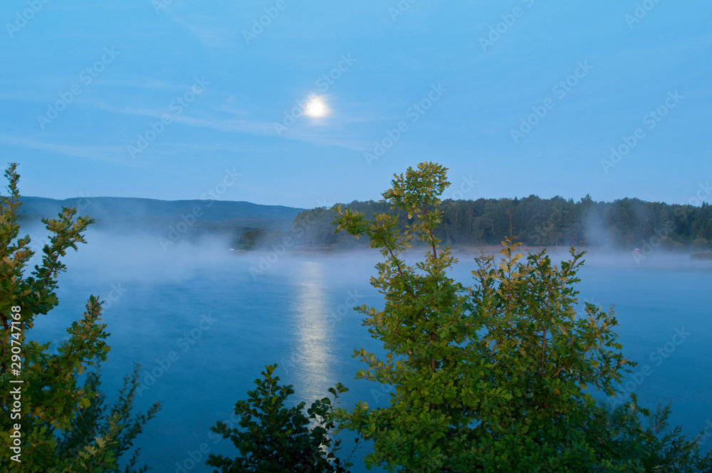 colorful moon on autumn lake at dawn with forest