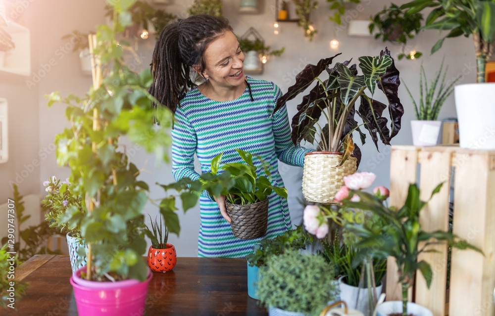 Young woman taking care of her potted plants at home Young woman taking care of her potted plants at home