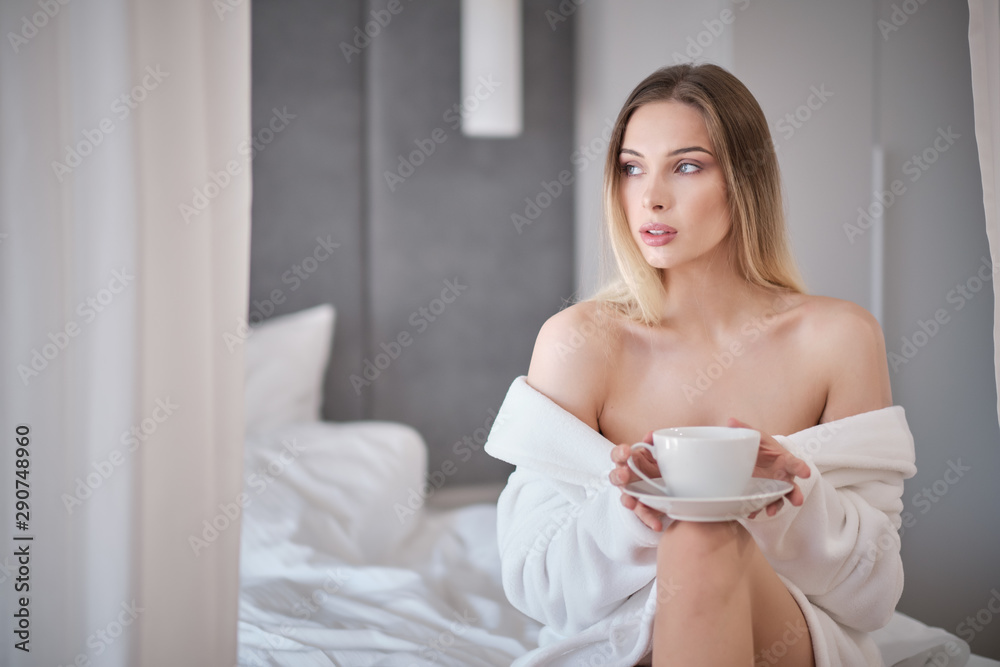 woman in a bathrobe drinks morning coffee in bed woman in a bathrobe drinks morning coffee in bed