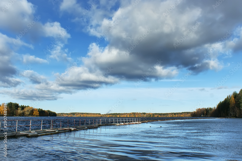 Vuoksa River in Finland. Sunny autumn day by the river. Blue water surface and clouds running into the distance. Scandinavian lifestyle. Vuoksa River in Finland. Sunny autumn day by the river. Blue water surface and clouds running into the distance. Scandinavian lifestyle.