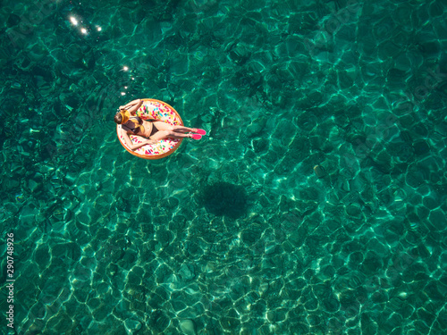 Top down view of a beautiful woman in a white bikini who is floating on a air mattress