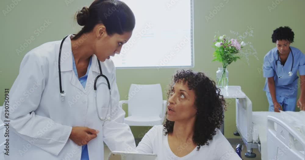 Front view of African american female doctor discussing medical report with disabled female patient Front view of African american female doctor discussing medical report with disabled female patient