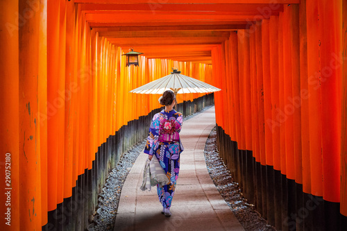 Fototapet Woman in traditional kimono and umbrela walking at torii gates, Japan