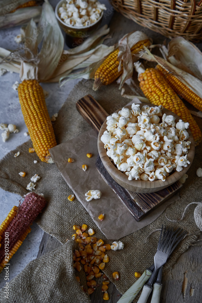 Traditional popcorn in a wooden bowl and corncobs on the table. Traditional popcorn in a wooden bowl and corncobs on the table.
