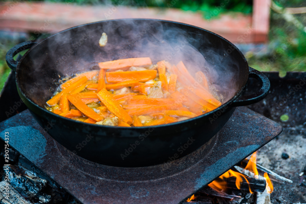 Roasted carrots with onions and meat in a cauldron. The process of cooking pilaf on the fire. Firefood Roasted carrots with onions and meat in a cauldron. The process of cooking pilaf on the fire. Firefood