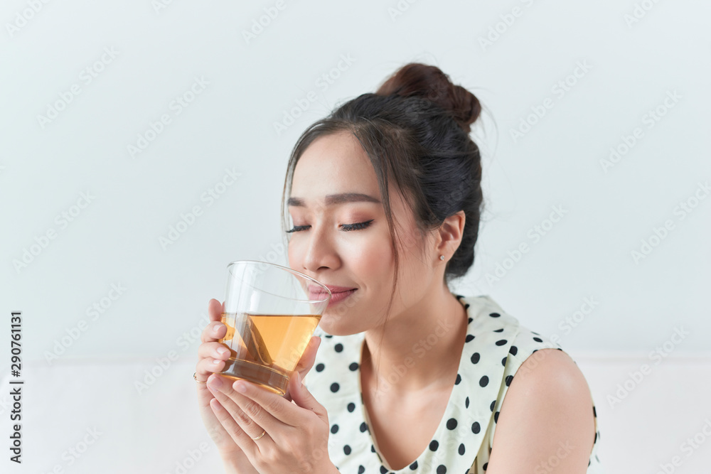 Happy asian woman sitting on her sofa holding cup at home Happy asian woman sitting on her sofa holding cup at home