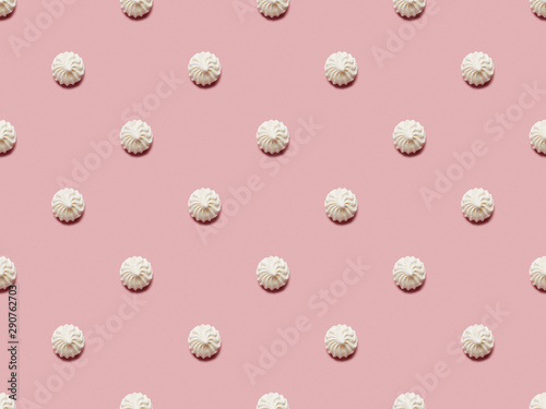 Flat lay with small white meringues on pink background