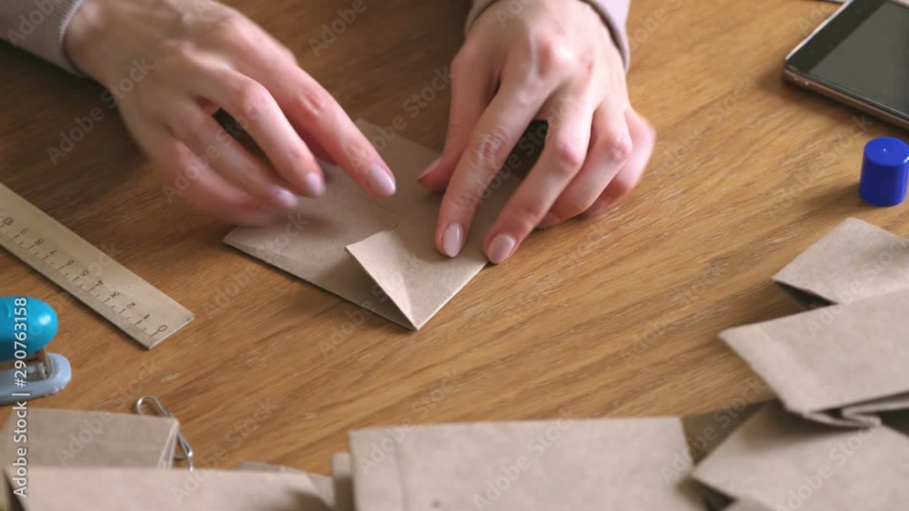Woman makes a paper bags from kraft paper. Hands close-up Woman makes a paper bags from kraft paper. Hands close-up