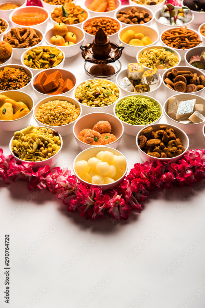 Rangoli of sweets and Farsan/snacks in bowls for Diwali with diya over white background Rangoli of sweets and Farsan/snacks in bowls for Diwali with diya over white background
