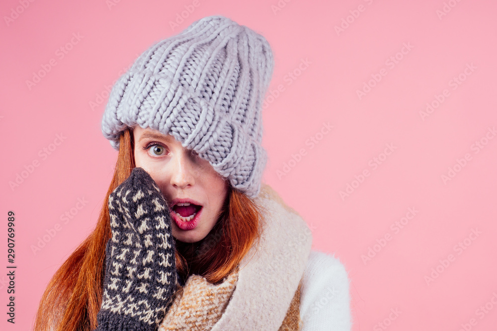 amazed and surprised redhaired ginger woman wearing stylish hat ,knitted mittens and sweater gossiping in studio pink background amazed and surprised redhaired ginger woman wearing stylish hat ,knitted mittens and sweater gossiping in studio pink background