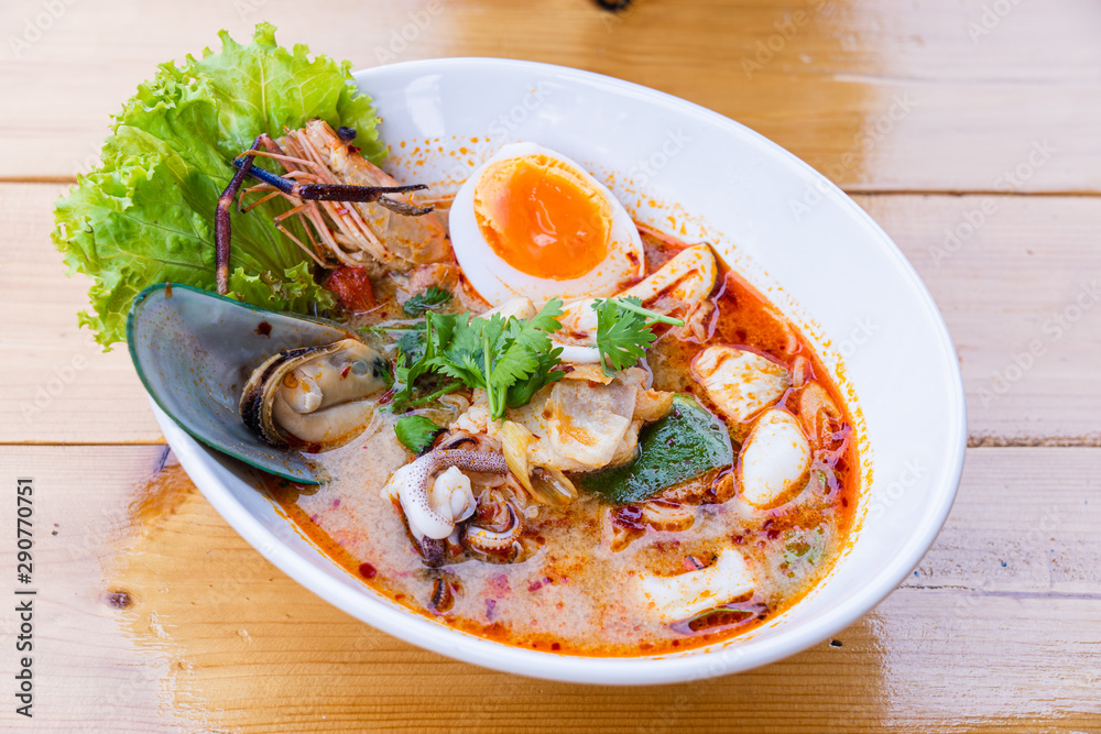 Traditional Thai food spicy soup with shrimp or tom yum seafood noodle in bow on wooden table with copy space. Traditional Thai food spicy soup with shrimp or tom yum seafood noodle in bow on wooden table with copy space.