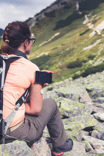 Active life of diabetics, woman hiking and checking glucose level with a remote sensor and mobile phone, sensor checkup glucose levels without blood. Diabetes treatment. Violet toned image.