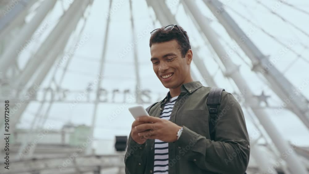 bi-racial man laughing and typing on smartphone bi-racial man laughing and typing on smartphone