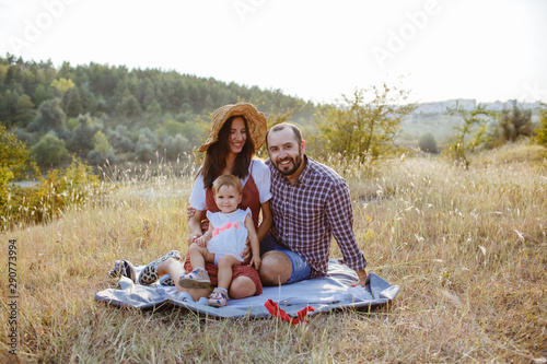 Beautiful family spending time on a field at sunset.