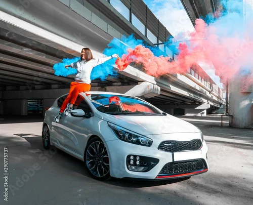 Obraz Ufna i piękna młoda kobieta w przypadkowych sportach jest ubranym obsiadanie na nowym samochodzie i radować się.