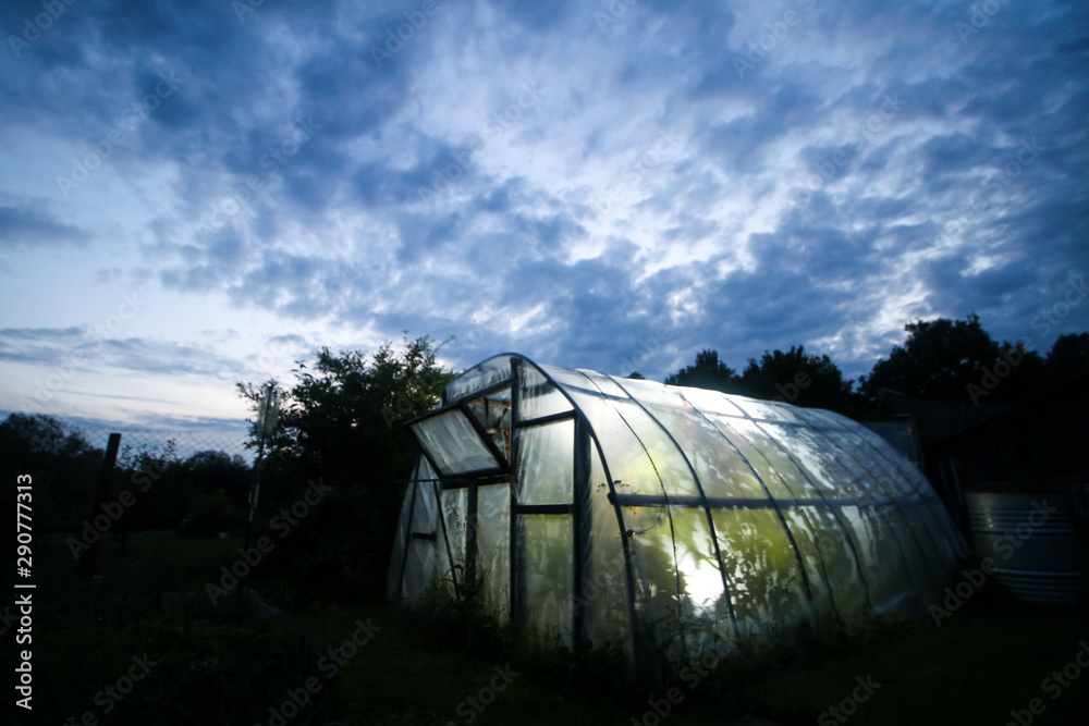 Beautiful evening view of cloudy sky and strobe light green house of tomatoe plants. Beautiful evening view of cloudy sky and strobe light green house of tomatoe plants.