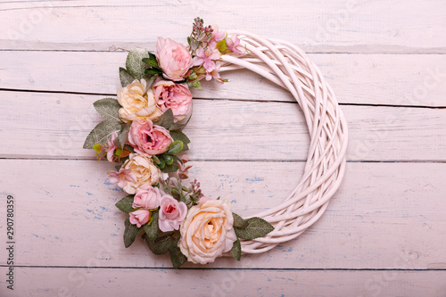 Door wreath made of artificial flowers and autumn plants on shabi white wooden background.