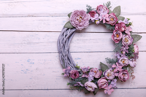 Door wreath made of artificial flowers and autumn plants on shabi white wooden background.
