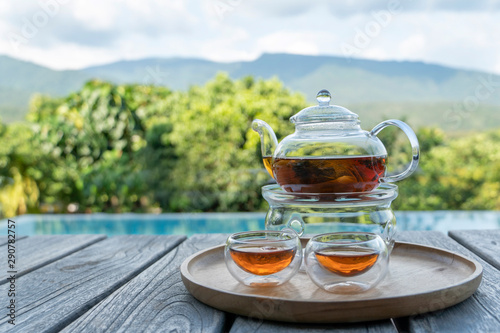 teapot pouring tea into cup with mountain lanscapes background. © byjeng