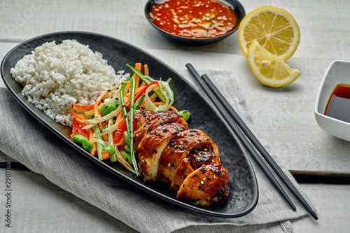 Traditional Japanese teriyaki chicken with salad made of cucumber, ginger, carrot, pepper and cabbage, rice, sesame, chili and soy sauces, lemon and edamame.