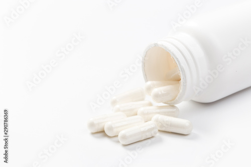 Pill bottle spilling medical pills onto surface isolated on a white background.