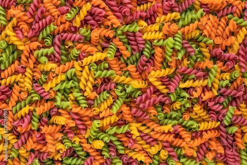 Background of colorful italian pasta. Culinary backdrop  food texture. Table top view. Abstract pattern of multi colored macaroni. Heap of raw pastas.