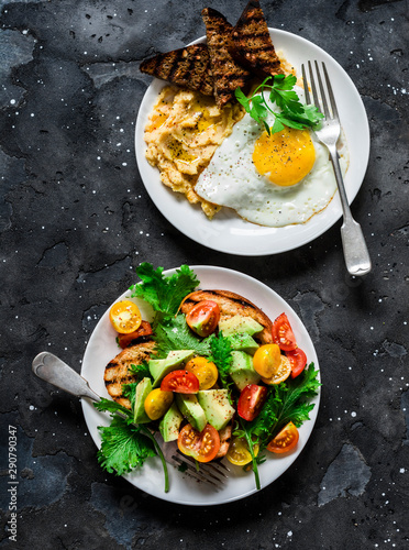 Savory breakfast - avocado, cherry tomatoes grilled bread salad and fried egg with hummus and rye croutons on dark background, top view